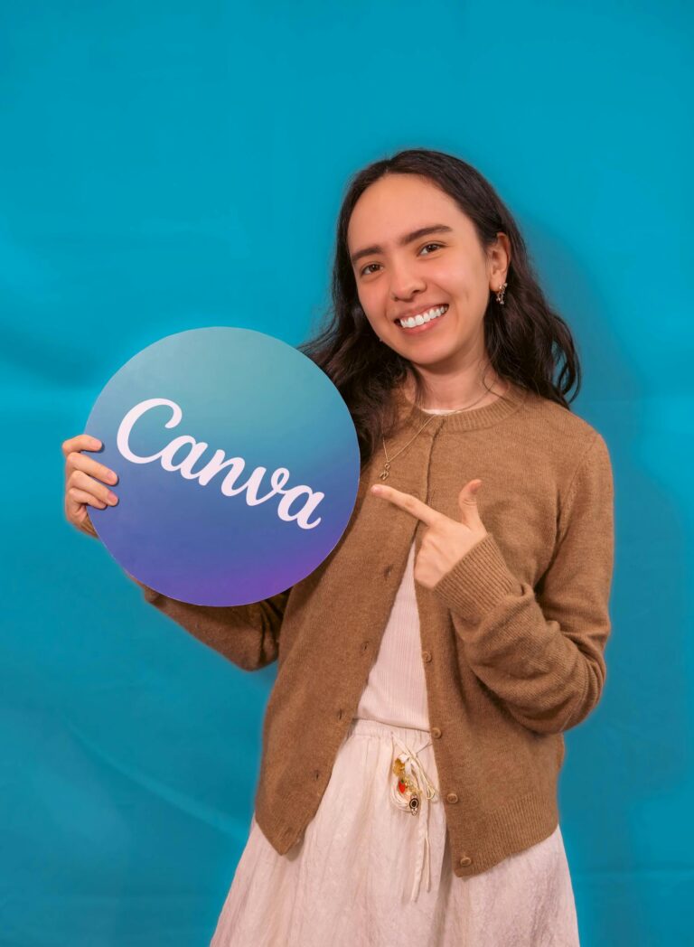 Happy woman holding Canva logo on a turquoise backdrop.